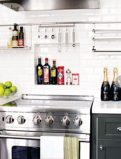 a stainless steel stove top oven sitting inside of a kitchen next to a wall mounted wine rack