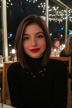 Woman with shoulder-length brown hair, wearing a black turtleneck, smiling in a warmly lit restaurant with string lights. Textured Bobs, Grown Out Pixie, Textured Bob, Corte Bob, Classic Bob, Asymmetrical Cut