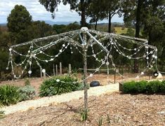 an outdoor gazebo with string lights on it in the middle of a garden area