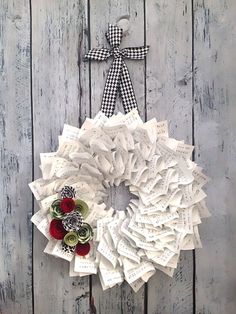 a wreath made out of old book pages and buttons on a wooden door with a bow