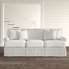 a white couch sitting on top of a hard wood floor next to a stair case