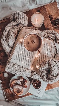 a cup of coffee and some doughnuts on a wooden tray with a book