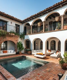 an outdoor swimming pool surrounded by patio furniture and potted plants in front of a house