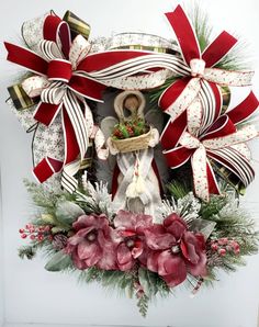 the wreath is decorated with red and white ribbons, flowers, and a virgin mary