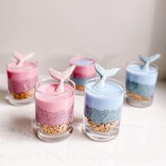 small glass cups filled with different colored sand and sea creatures on top of each other