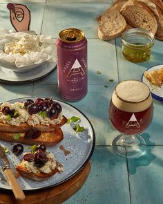 a table topped with bread and other food next to glasses of wine on top of a blue tiled floor