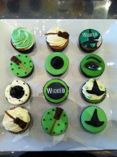 cupcakes decorated with green frosting and black icing on a white tray