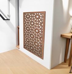 a white wall with a decorative wooden panel on it's side next to a table and chair