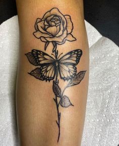 a black and white rose with a butterfly on it's leg tattoo by the artist