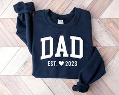 a sweatshirt with the words dad est 2020 printed on it sitting on a wooden floor