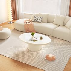 a living room filled with white furniture and decor on top of a hard wood floor