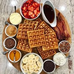 waffles, fruit, and other foods are arranged on a wooden platter