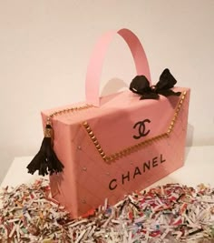 a pink chanel bag cake sitting on top of confetti sprinkles