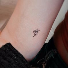 a small flower tattoo on the left wrist is shown in black and white ink,