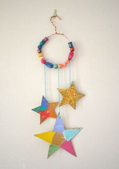 a multicolored star mobile hanging on a wall next to a white wall with a string