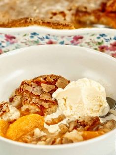 a white bowl filled with fruit and ice cream on top of a floral table cloth