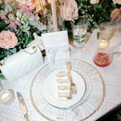 a plate with cake on it sitting next to flowers and candles in front of a vase