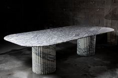 a white marble table sitting on top of a cement floor next to a brick wall