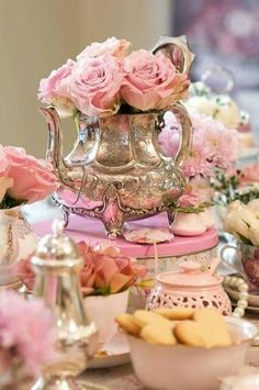 a table topped with lots of pink flowers and tea pots on top of each other