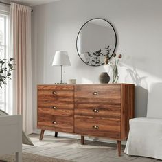 a wooden dresser sitting in front of a mirror on top of a wall next to a lamp