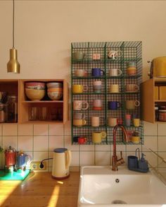 a kitchen area with a sink, counter top and shelves filled with dishes on the wall