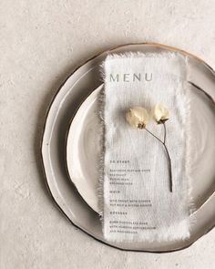 a white plate with a napkin and two flowers on it, sitting next to each other