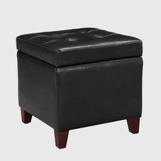 a black ottoman with wooden legs and a buttoned up seat on the bottom side