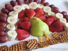 a plate with waffles, strawberries, bananas and a green bird on it