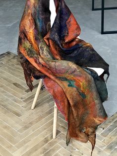 a multicolored scarf sitting on top of a white chair next to a wooden floor