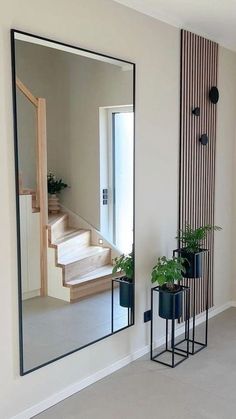 a mirror sitting on the side of a wall next to potted plants and a stair case