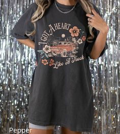 "Comfort Colors I Got A Heart Like A Truck Shirt -UNISEX Comfort Colors C1717 T-SHIRTS -100% ring-spun cotton - Preshrunk, soft-washed, garment-dyed fabric  -Set-in sleeves  -Double-needle stitched sleeves and bottom hem  -Twill taped shoulder-to-shoulder  -1\" ribbed collar with double-needle topstitched neckline Please order 1 or 2 sizes up for an oversized look. These ultra soft pigment dyed shirts are one of our best sellers! I DO NOT ACCEPT EXCHANGES OR RETURNS: all items are made to order. PROCESSING AND SHIPPING 3-5 business days for processing Allow 1-7 business days for shipping Please make sure you put the right address before purchasing!  CARE INSTRUCTIONS Wash inside out with similar colors Tumble dry low or hang to dry Try not to iron Machine wash cold *How to Place an Order* Band Merch Crew Neck Top With Heart Graphic, Short Sleeve Graphic Tee With Heart Graphic, Heart Graphic Short Sleeve Graphic Tee, Concert Short Sleeve Pre-shrunk Tops, Black Band Merch Top With Heart Graphic, Retro Summer Tops With Heart Graphic, Band Merch Cotton Top With Heart Graphic, Retro Cotton T-shirt With Heart Graphic, Cotton Band Merch Top With Heart Graphic