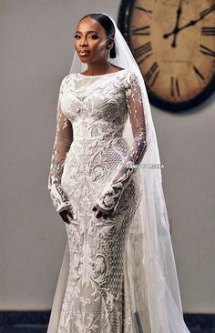 a woman in a wedding dress standing next to a clock