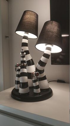 two black and white lamps sitting on top of a table next to a lamp shade