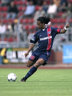 a man kicking a soccer ball on top of a field