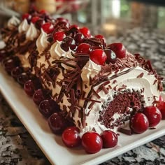 a piece of cake on a plate with cherries around it and chocolate frosting