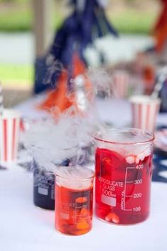 two beakles filled with red liquid sitting on top of a white table covered in american flags