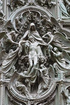 an ornate sculpture on the side of a building with angels and other people around it