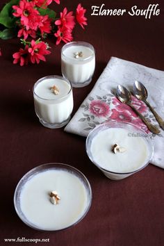 three candles sitting on top of a table with spoons and flowers in the background