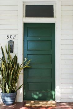 a green front door with a potted plant next to it and the number 922