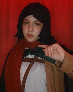 a young woman wearing a black and brown hoodie is posing for the camera with red curtains behind her