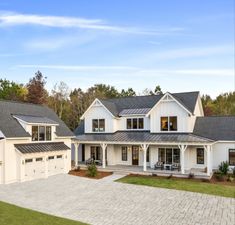 a large white house with two garages and lots of windows on the front of it