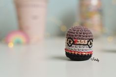 a small crocheted hat sitting on top of a table next to a cup