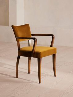 a yellow chair sitting on top of a hard wood floor next to a white wall