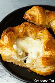 two croissants on a black plate with butter and sour cream in them