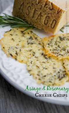 cheese crispes on a white plate with rosemary garnish and the word asiago written in cursive font