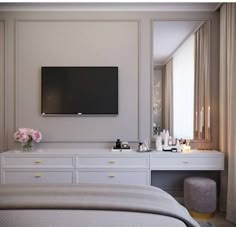 a bedroom with a large flat screen tv mounted to the wall above a dresser and bed