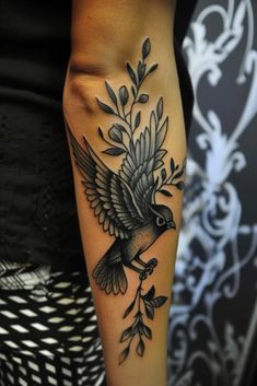 a woman's arm with a bird and leaves tattoo on the side of her leg