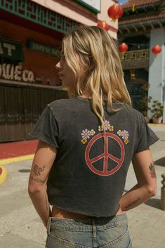 Mineral washed graphic t-shirt. Vintage-style back graphic print with peace sign and flowers. Chest print with flower and "Made With Love" text. Round neckline. Short sleeves. Lettuce-edge cuffs and hem. Cropped length. Relaxed fit. 100% Cotton. Imported top designed and printed in LA. Model wears size S. Peace Sign Tee Shirt, Floral Peace Sign, Graphic Baby Tee, Baby Graphic Tees, Love Text, Vintage Canvas, Baby Tee, Peace Sign, Made With Love