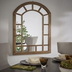 a dining room table with plates and bowls on it, in front of a mirror