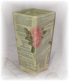 an open book with pink flowers on it and pearls around the edges, sitting on a white surface